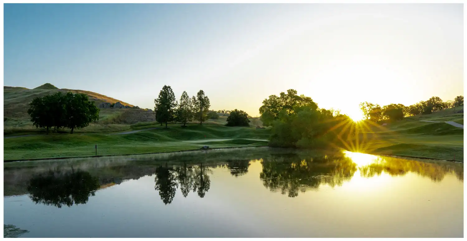 A sunset view of a golf course behind a body of water